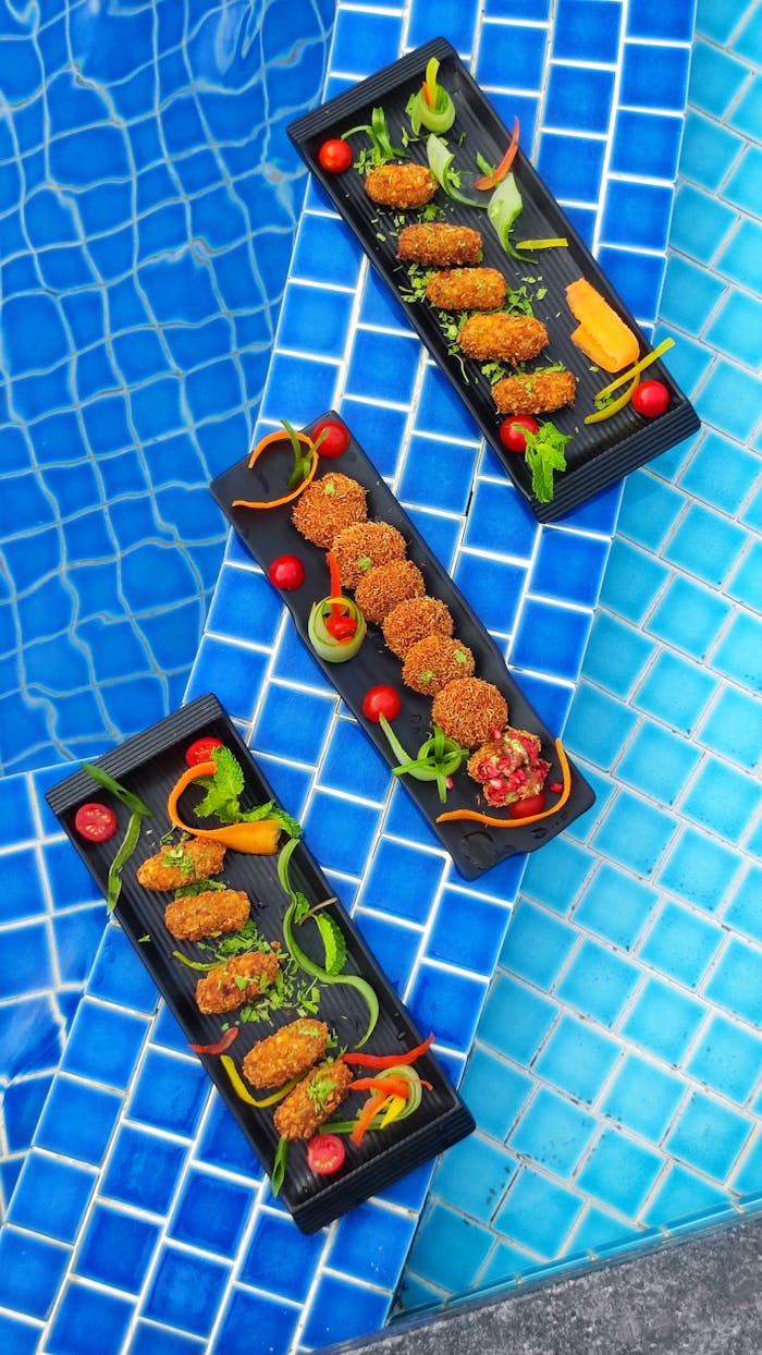 Three skewers of food on a tray next to a pool