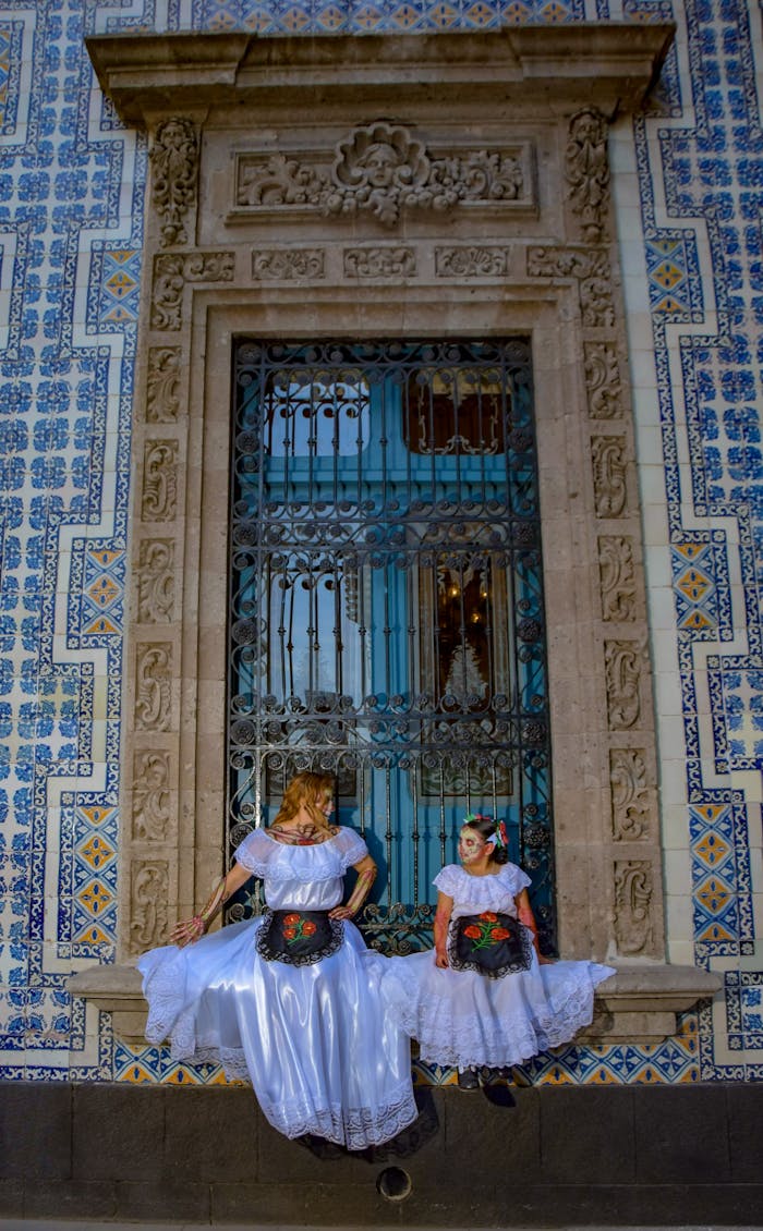 Two women in traditional dress pose in front of a blue door